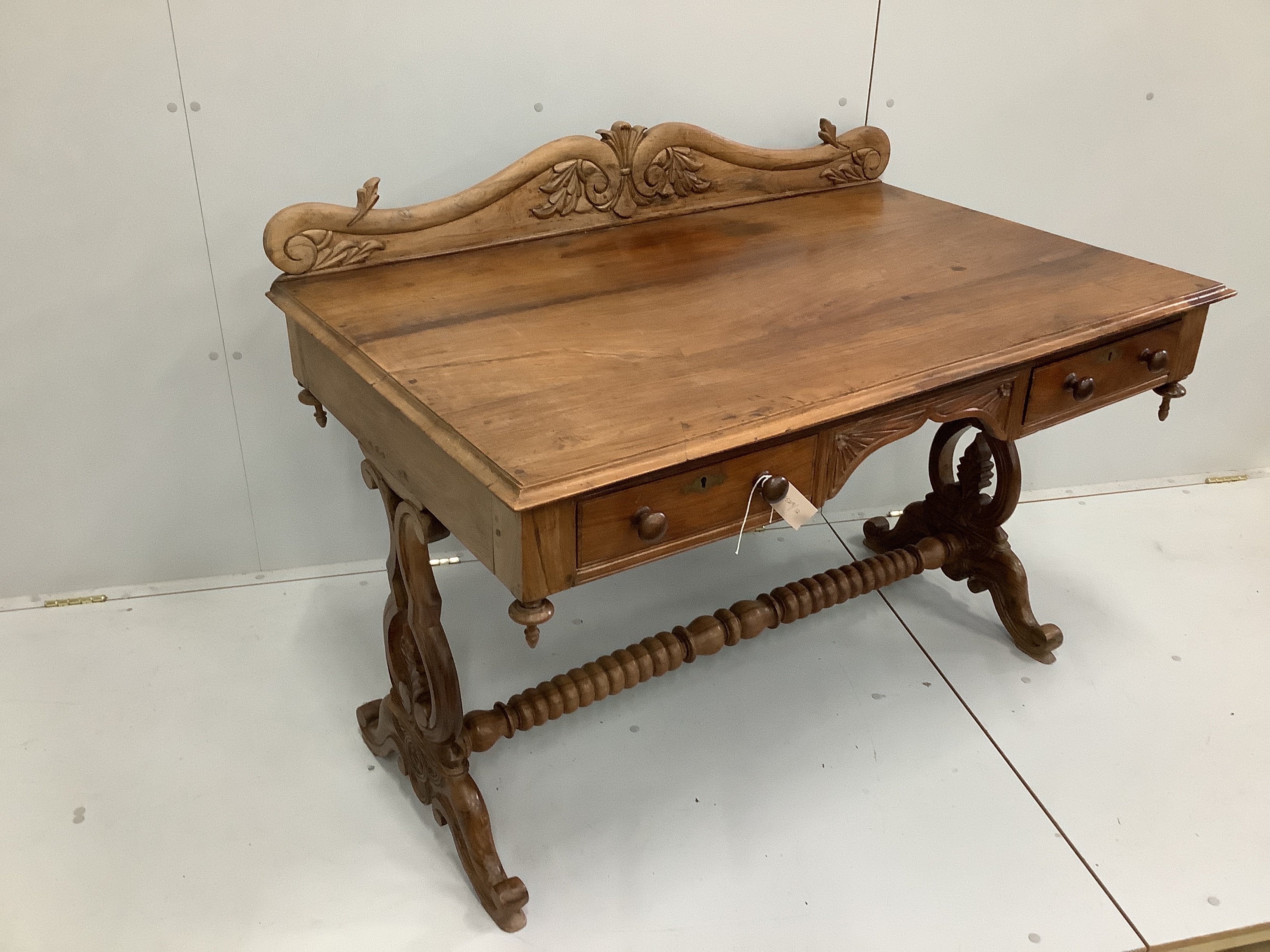 An Anglo-Indian carved hardwood writing table, two frieze drawers, on scrolled end supports, width 121cm. depth 74cm, height 92cm